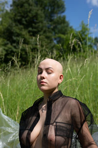 Sensual woman with eyes closed standing amidst grass standing outdoors