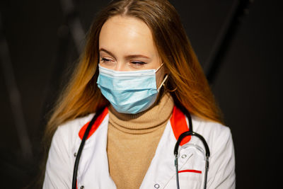 Young woman wearing mask while standing against wall