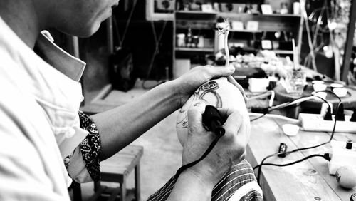 Midsection of man making tattoo on object in workshop