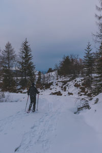 Man skiing on snow covered field against sky