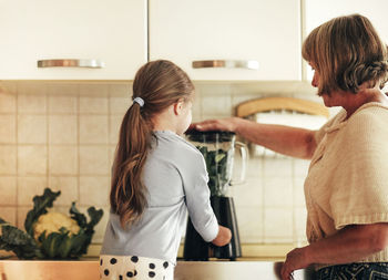 Side view of woman standing against wall at home