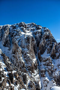 Low angle view of snowcapped mountain against blue sky