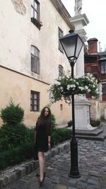 Full length of woman standing on street against building