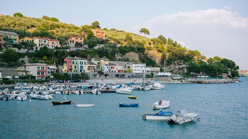 Boats in sea by townscape against sky