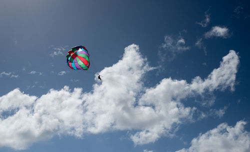 Low angle view of man parasailing against sky