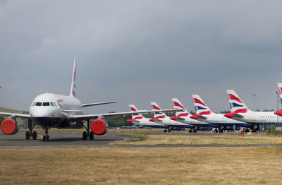 Airplane flying over airport runway against sky