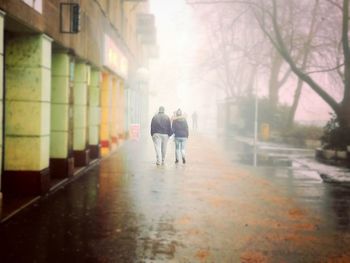 Rear view of two people walking on street