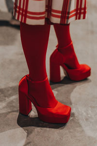 Women's legs in red tights and designer silky high heels. vertical fashion shot