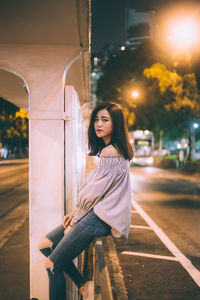Portrait of beautiful young woman on road at night