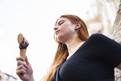 Young woman enjoying delicious ice cream in city