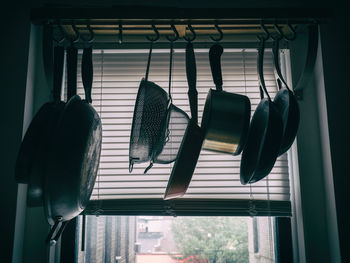 Cooking pans hanging in front of a window with shades