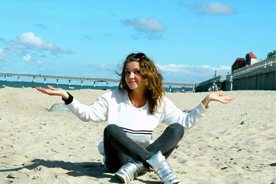 Portrait of smiling woman gesturing while sitting at beach