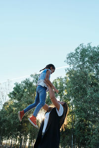 Low angle view of woman standing on tree against clear sky