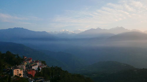 Scenic view of townscape by mountains against sky