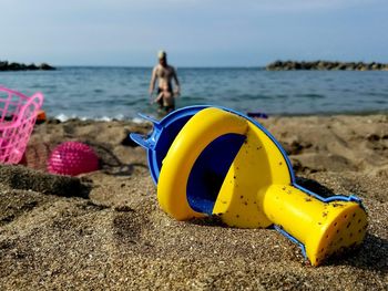 Close-up of yellow ring on beach against sky