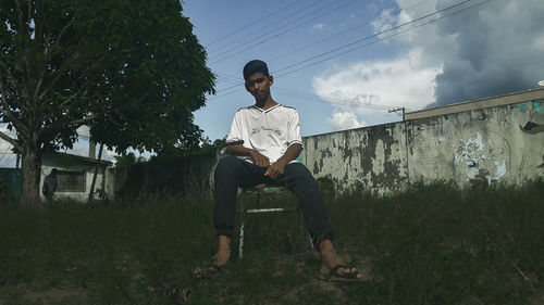 Full length of young man sitting on chair in lawn