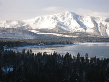 Scenic view of lake by snowcapped mountains against sky