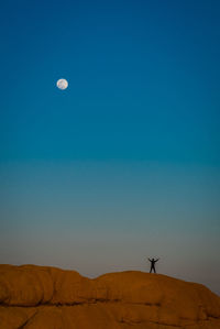 Rear view of man standing on mountain against clear sky at dusk