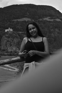 Portrait of a smiling young woman sitting on rock