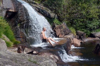 Man sitting in waterfalll