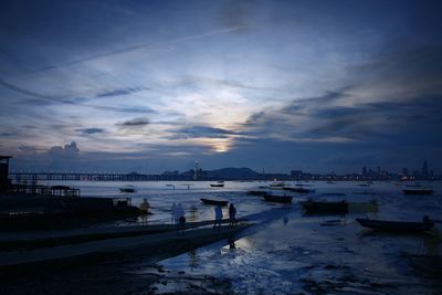 Boats moored at harbor during sunset