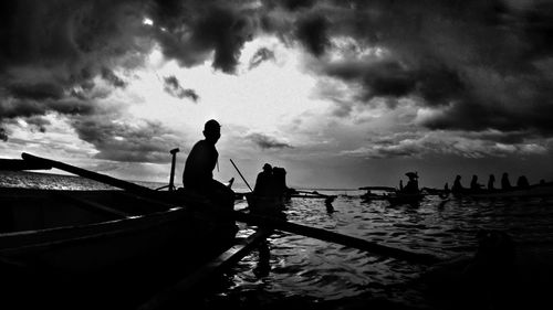 Silhouette men on boat against sky