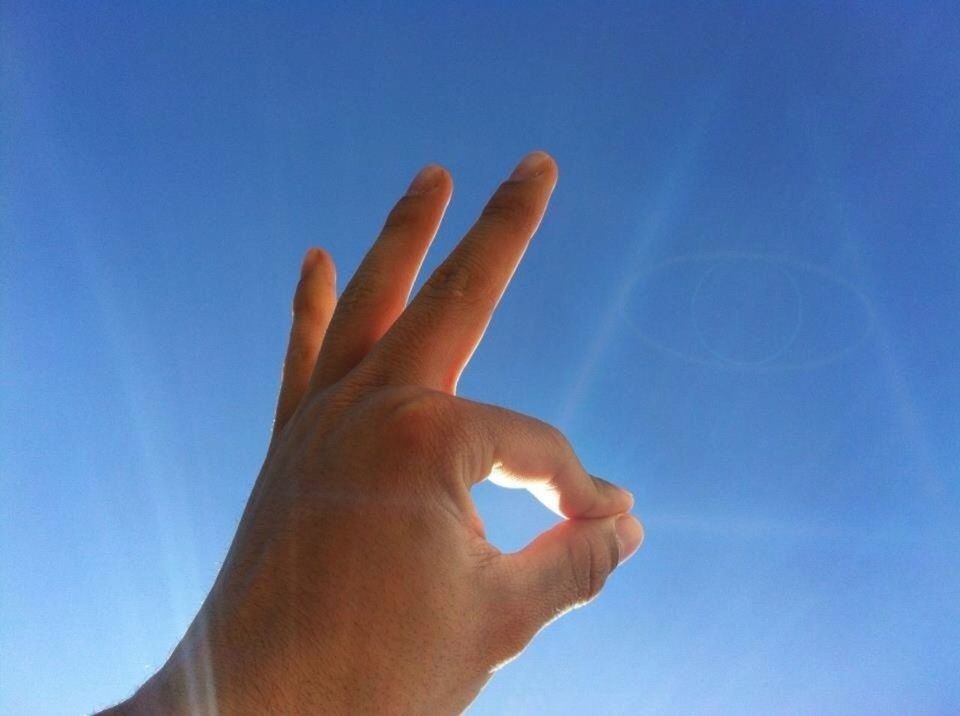 person, part of, blue, cropped, human finger, low angle view, clear sky, sky, holding, personal perspective, unrecognizable person, close-up, sunlight, lifestyles, copy space, leisure activity, outdoors