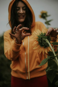 Midsection of woman holding flower standing at home