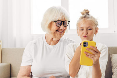 Portrait of young woman using mobile phone while sitting at home