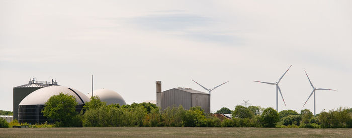 Wind turbines on field against sky