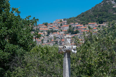 Trees and buildings in town against clear sky