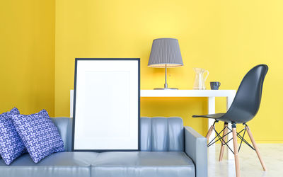 Empty chairs and table against yellow wall at home