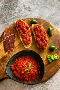 Slices of fresh bread spread with homemade lutenica on a wooden board