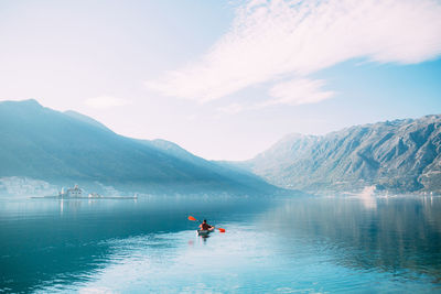 People on lake against mountain range