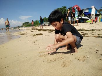 Full length of boy playing with sand at beach