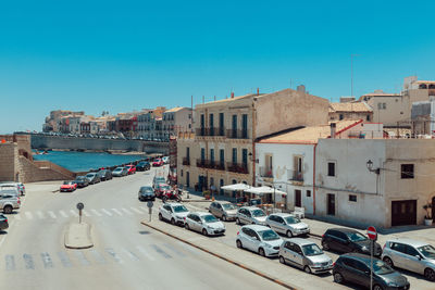 Cars on street in city against clear blue sky