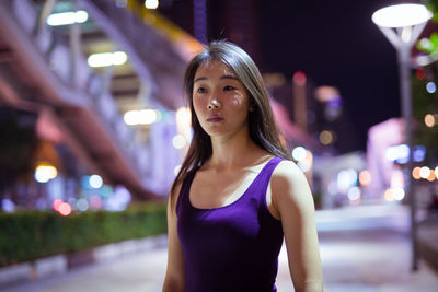 Portrait of beautiful woman standing in city at night
