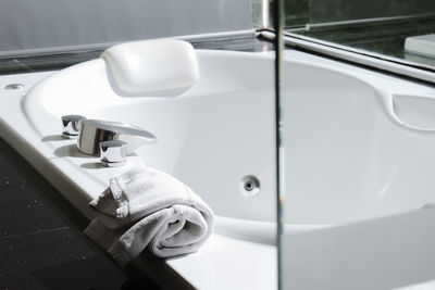 Close-up of hand holding faucet in bathroom