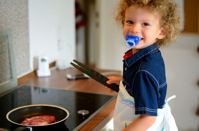 Portrait of smiling girl preparing food in kitchen at home