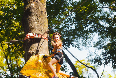 Low angle view of young woman sitting on tree