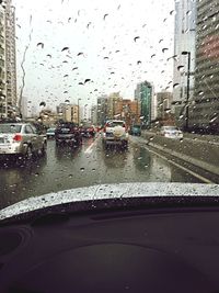 Cars on road seen through wet window in rainy season