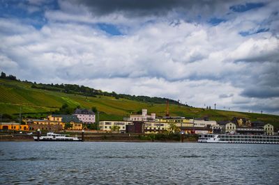 Scenic view of river by buildings against sky