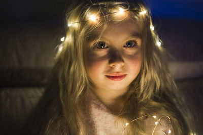 Portrait of girl with illuminated string lights at night