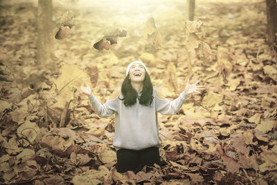 Portrait of young woman with arms raised standing on land