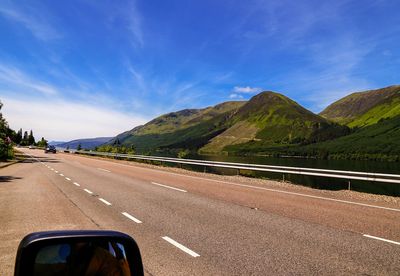 Road by mountains against sky