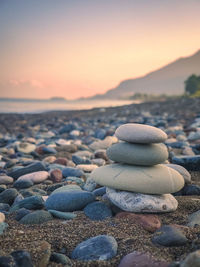 Rocks on beach against sky during sunset