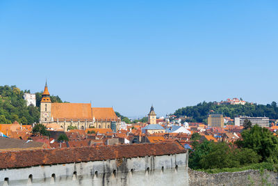 Buildings in city against clear blue sky