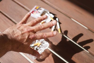 Cropped hand of man over cigarettes on table