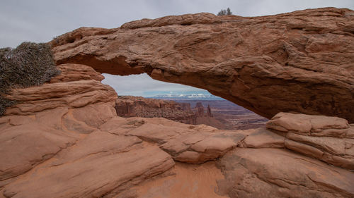 Full frame view of mesa arch with snow capped mountains in the background
