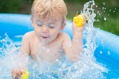 Cute boy splashing in wading pool